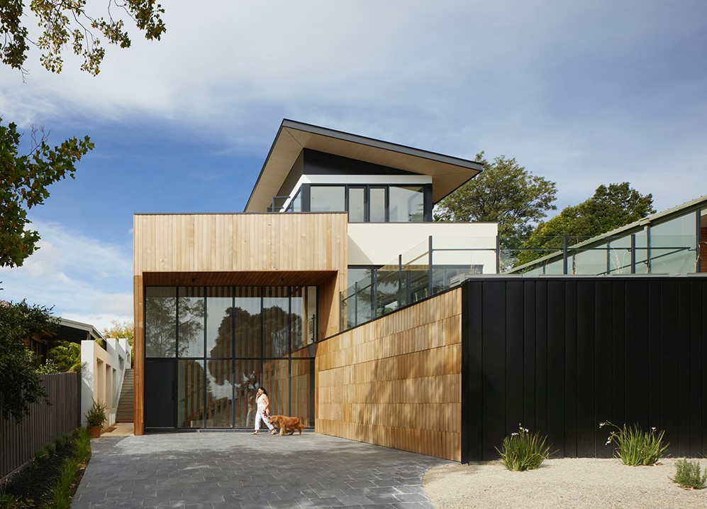 Outdoor view of a housing property with a person walking a dog out front.